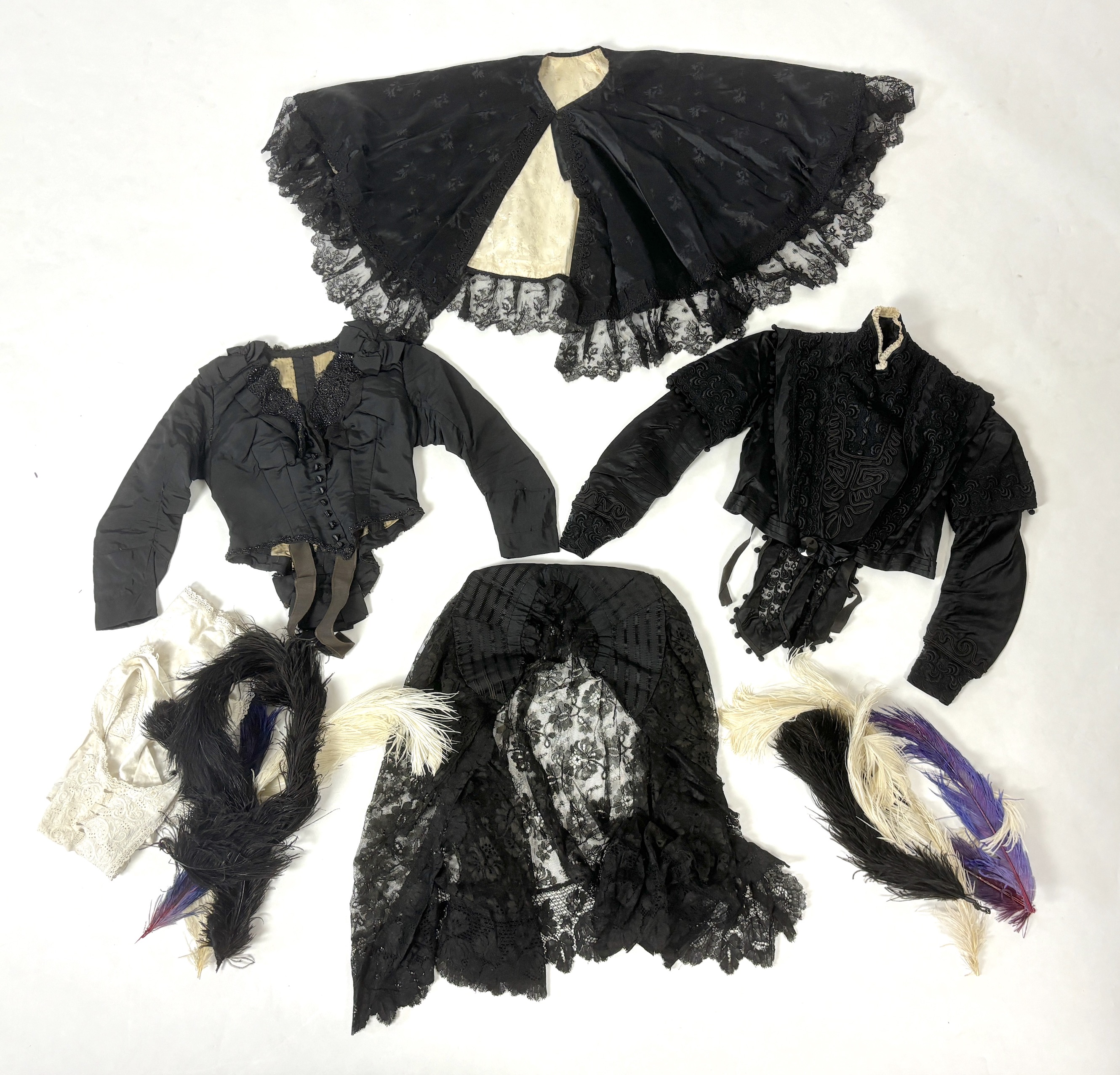 Two lady's Victorian black satin and lace, bead trimmed bodices, together with a black lace cape, a black satin cape, a small collection of coloured feathers and a child’s white worked pinafore
